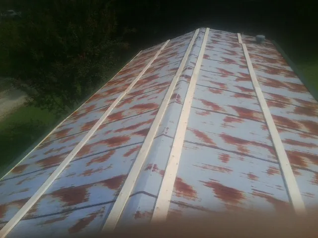 Rusted metal roof panels with new wood purlins before replacement — Storm Damage Roof Repair in Shannon City by Roofing Brothers