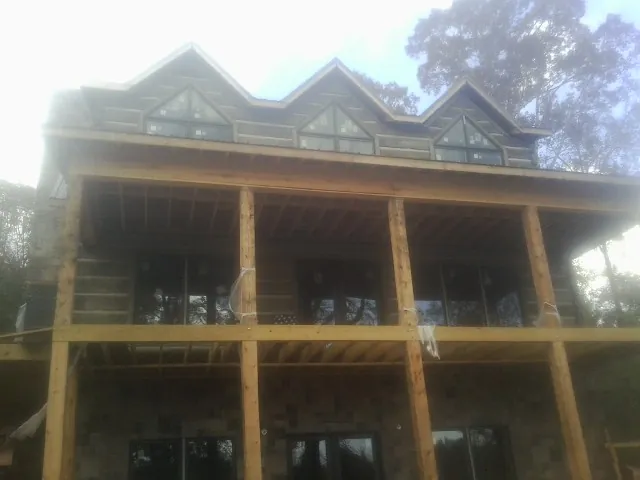 Dormers and porch framing on a large log home under construction — Roof Coating work by our crew in Shannon City