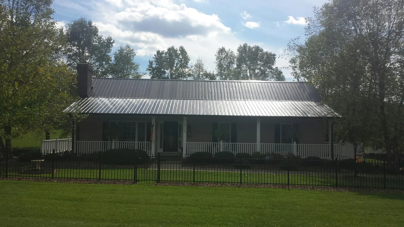 Gray metal roof on a brick ranch with a full width front porch — Gutter Guard Installation work by our crew in Shannon City