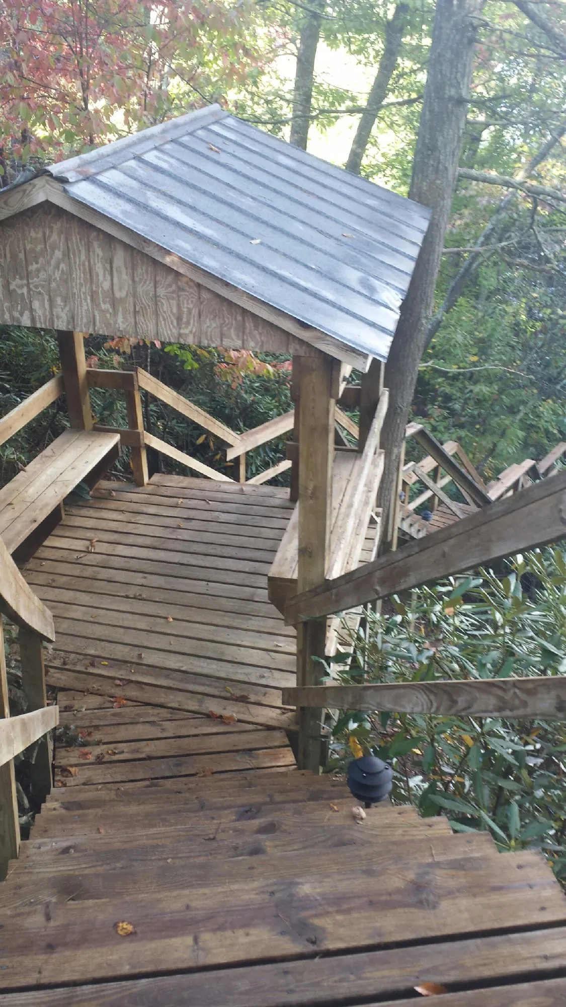 Metal roofed shelter over wooden steps on a wooded walkway — Skylight Repair & Installation work by our crew in Shannon City