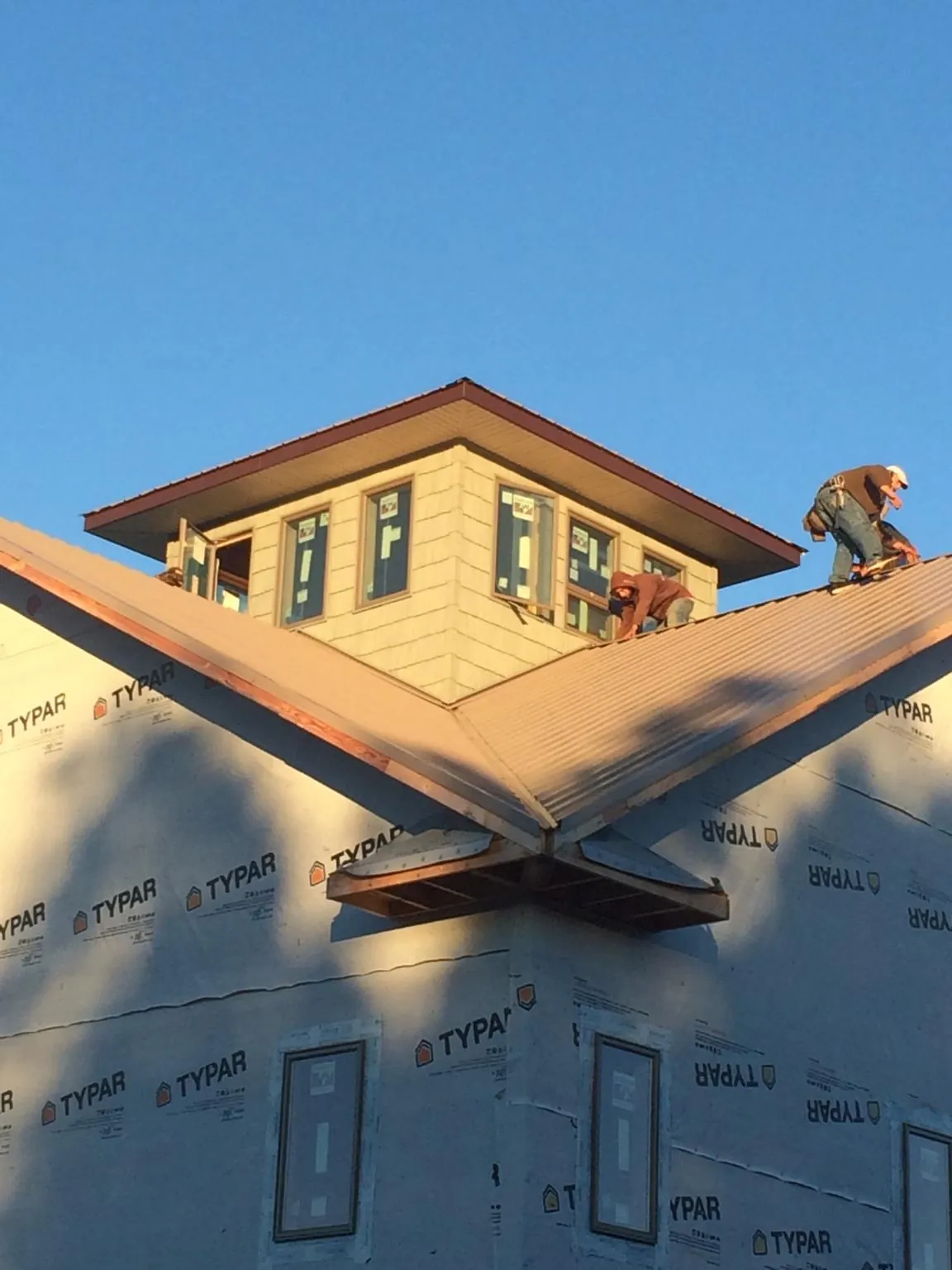 Roofers working around a rooftop cupola on a new metal roof at sunset — Roof Waterproofing in Shannon City by Roofing Brothers